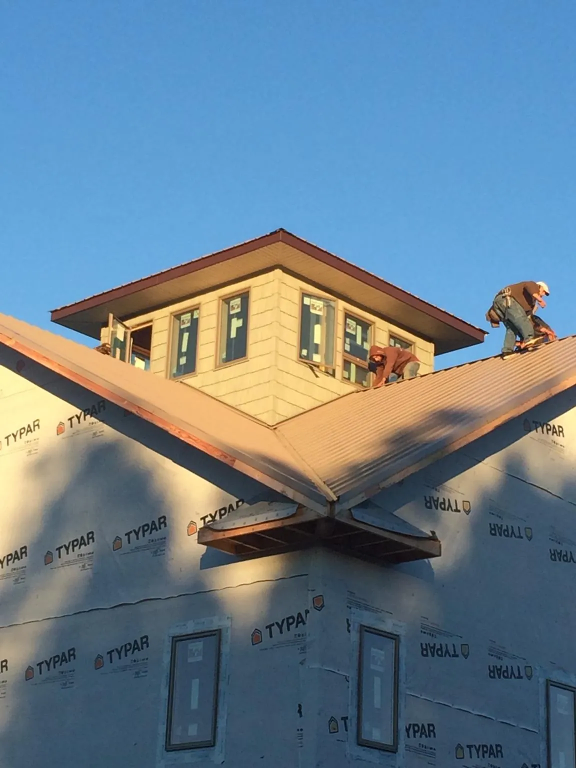 Roofers working around a rooftop cupola on a new metal roof at sunset — Roof Waterproofing in Jefferson City by Roofing Brothers
